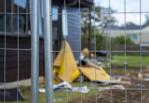 Temporary construction fence protecting residential property under repair. Selective focus on fence.